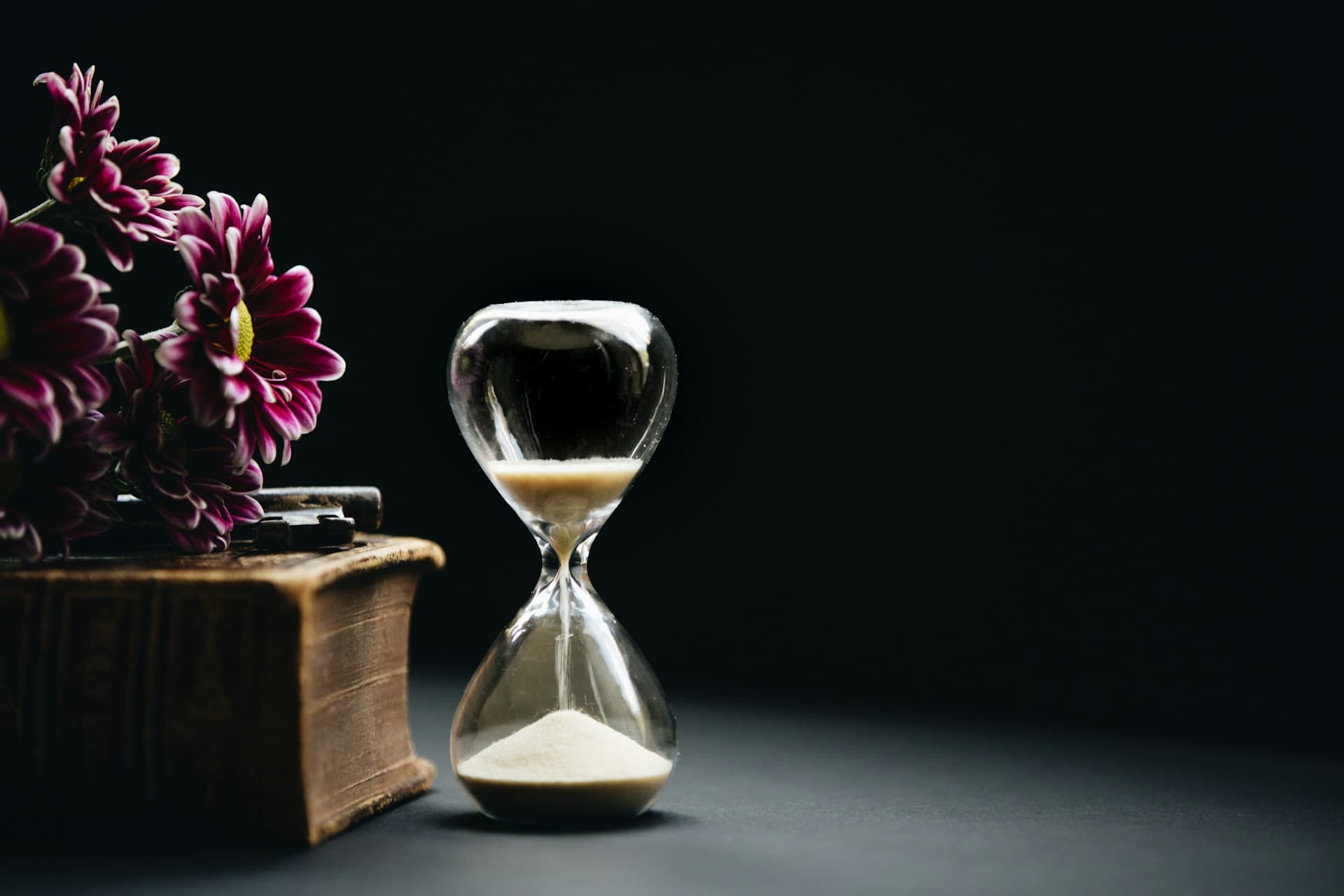 Hourglass with flowers — time passes, wisdom stays